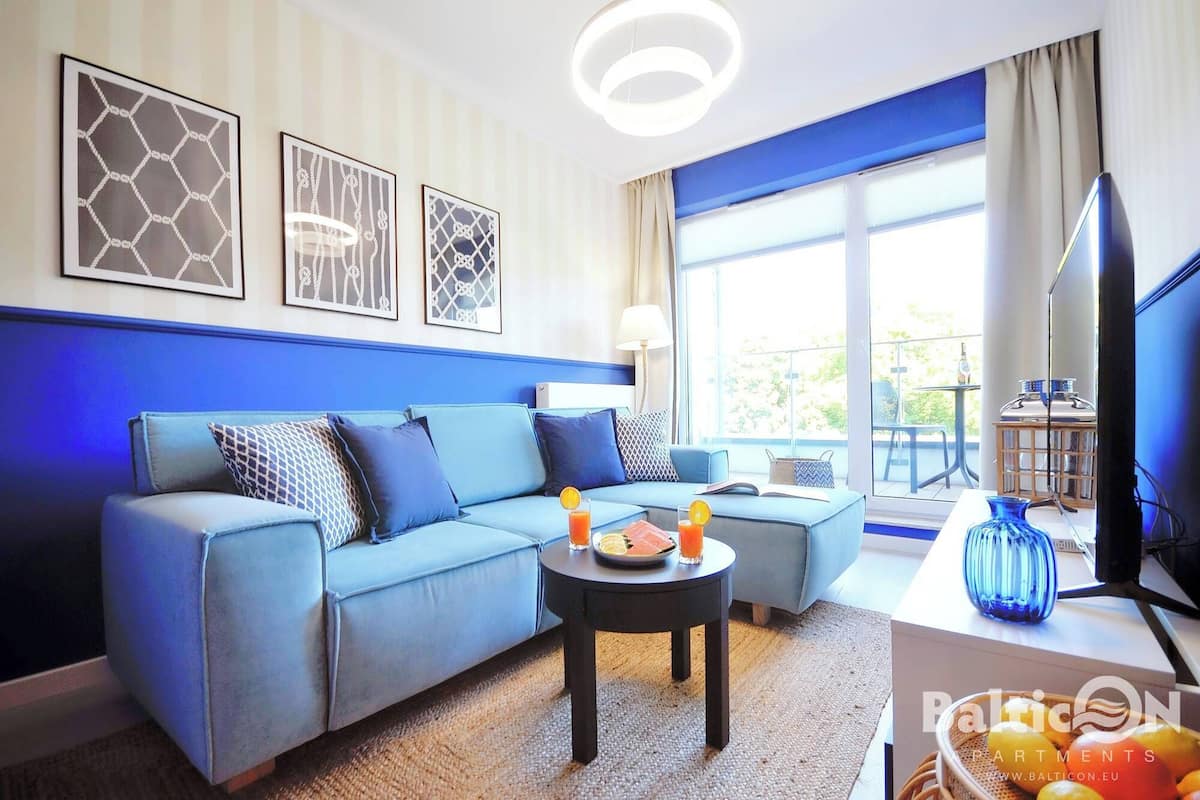 Ein modernes Wohnzimmer mit einem blauen Sofa, einem Couchtisch mit Getränken und einem Fernseher.