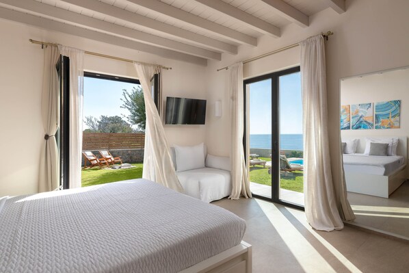 A bedroom with a bed, a TV, a balcony with a pool, and a view of the sea.