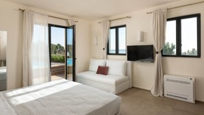 Een hotelkamer met een bed, een bank, een televisie en uitzicht op de omgeving.