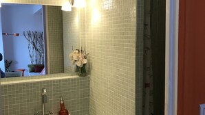A bathroom with a white sink, a mirror, and a shower area. - Very bright F2 with terrace and panoramic view of the Port <br> (Sète)