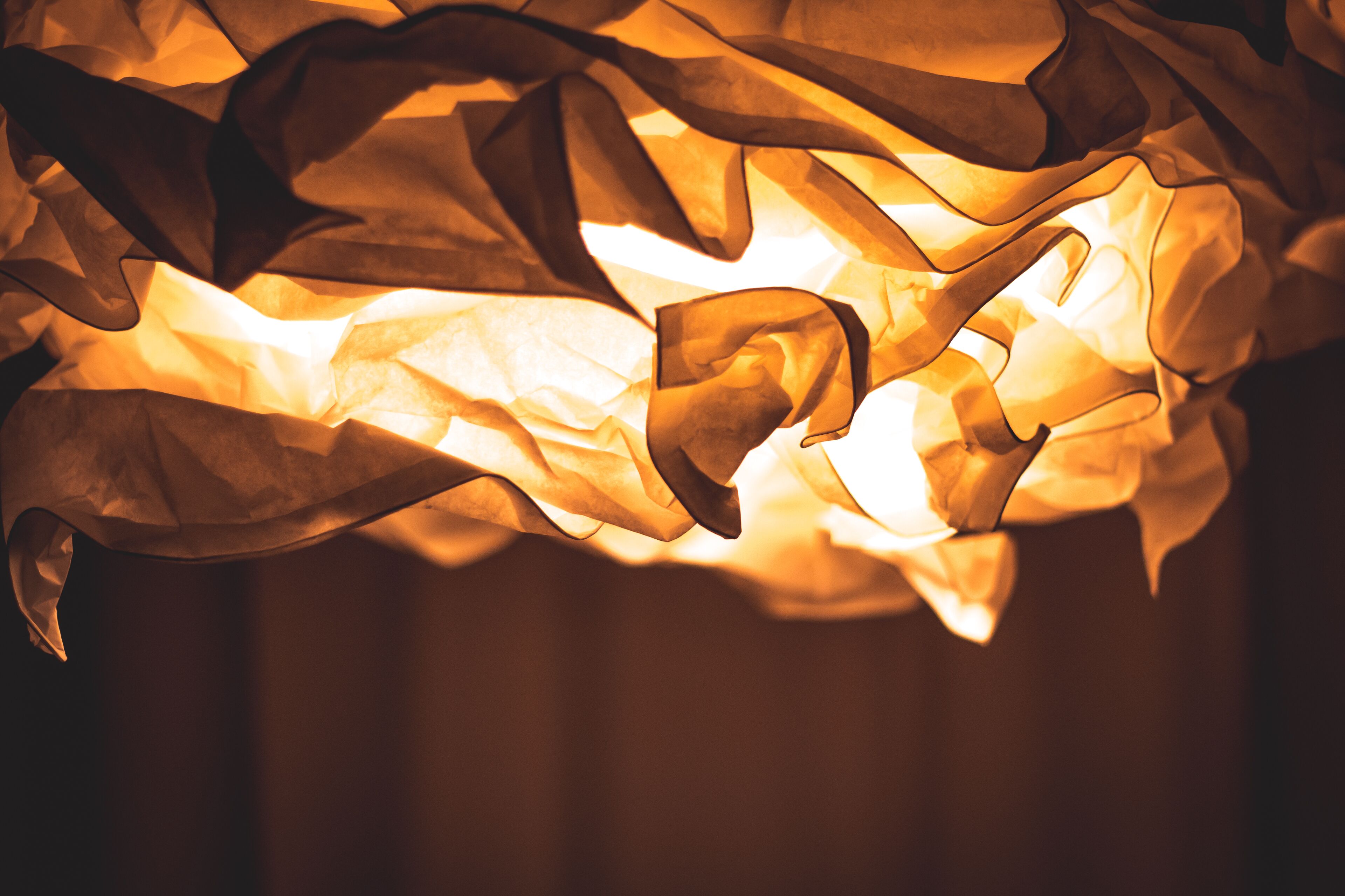 A close-up of crumpled paper with a warm glow, possibly from a light source.