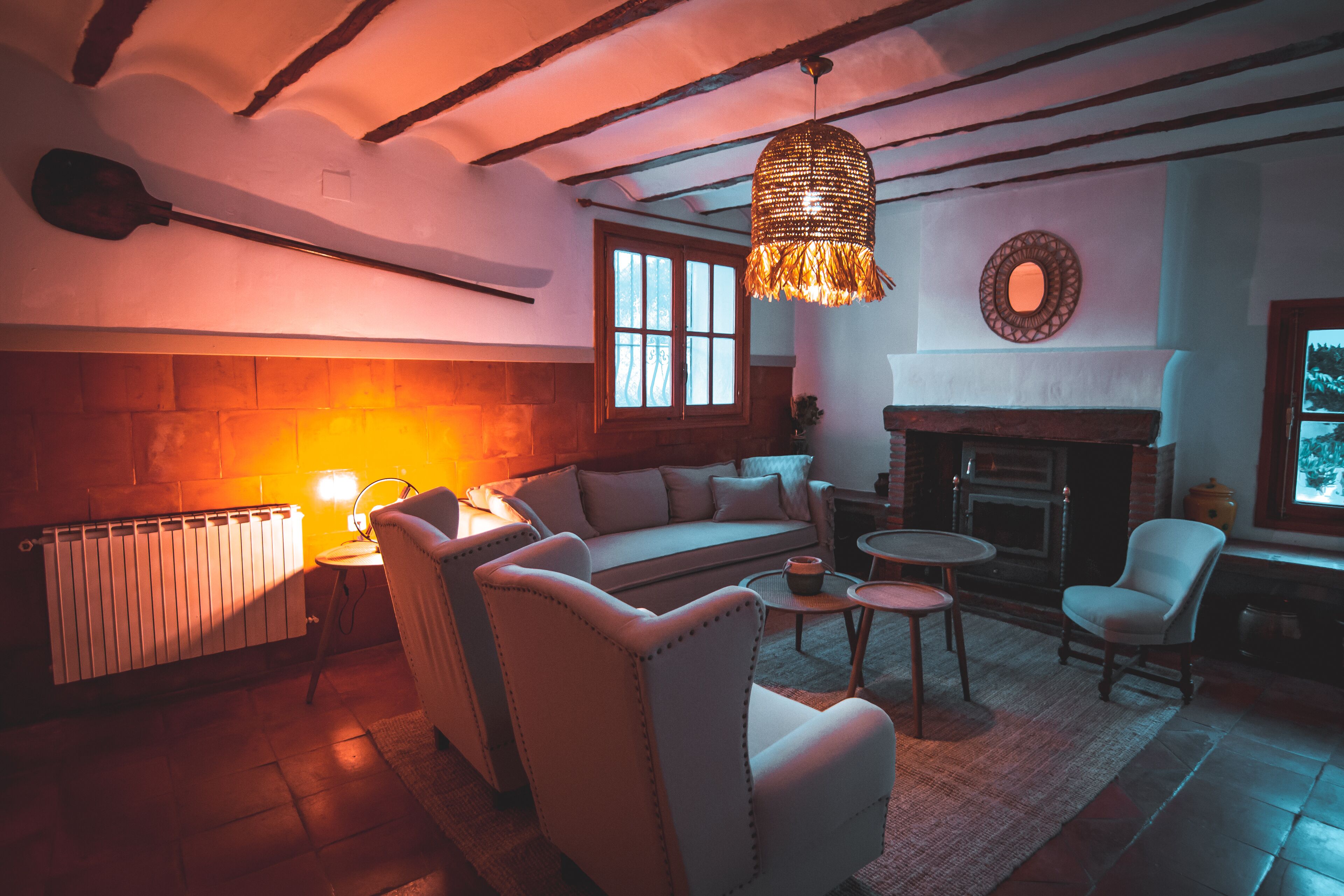 A cozy living room with a fireplace, comfortable seating, and a hanging light fixture.