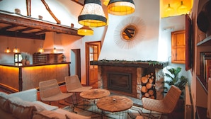 Una sala de estar acogedora con chimenea, sillones de mimbre e iluminación colgante.