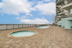 Un espace piscine sur le toit, comprenant deux piscines, une rambarde en métal et un escalier menant à un niveau supérieur.