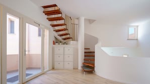 Un interior moderno con escalera de madera, puertas correderas de vidrio y pared blanca.
