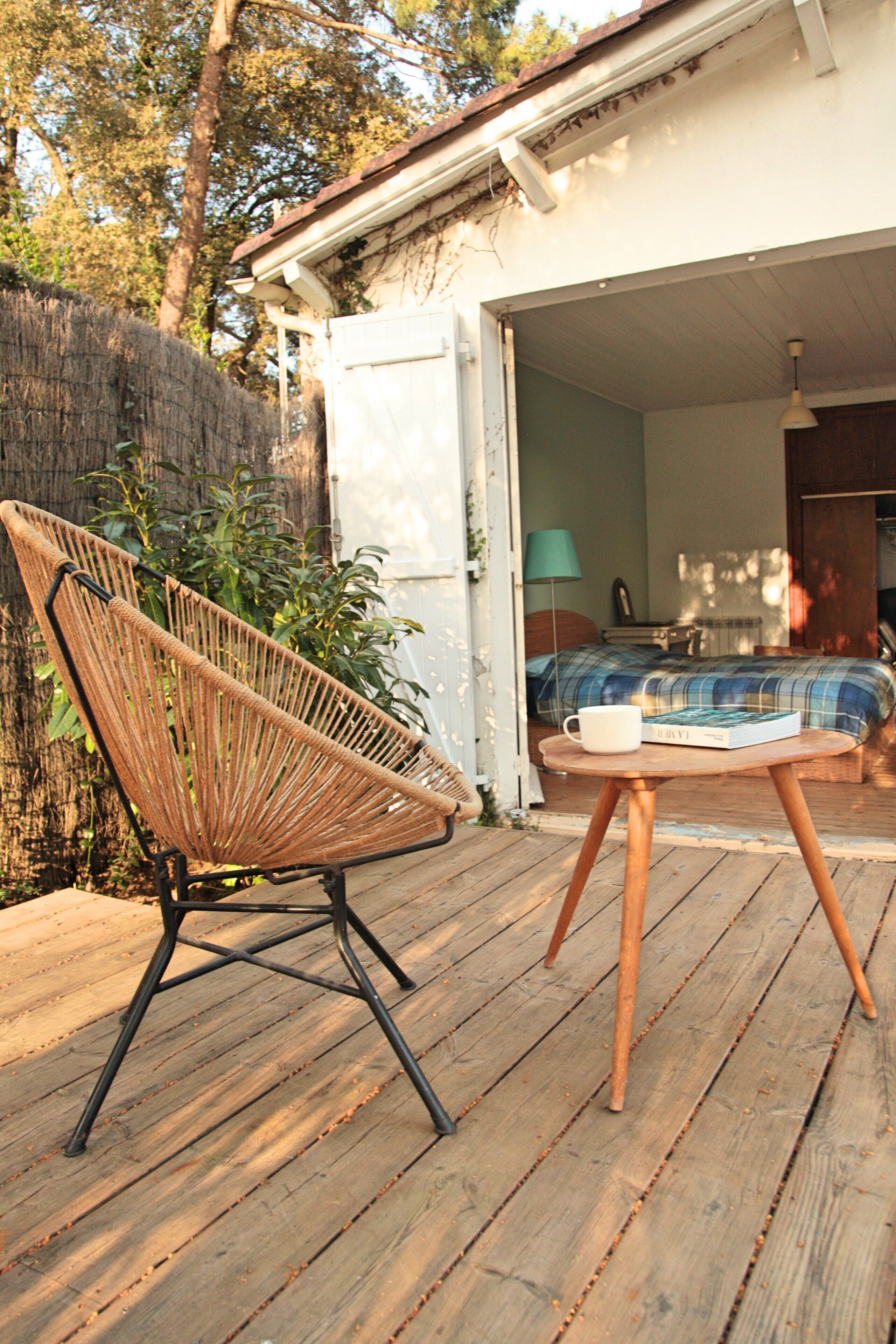 A wooden deck with a wicker chair and a small round table.
