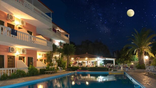 A nighttime view of a hotel with a swimming pool, a bar, and a moon in the sky. - Flamingo Apartments by CorfuEscapes (Corfu)