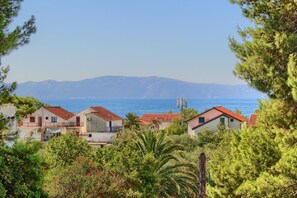 A coastal residential area with houses, a clear view of the sea, and mountains in the background.