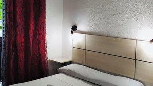 A hotel room with a bed, a nightstand, a lamp, and a window with curtains. - Pension Rivera (Madrid)
