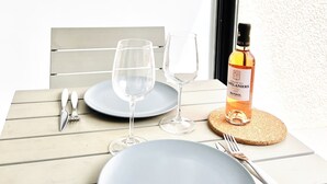 A dining table set with plates, wine glasses, cutlery, and a bottle of wine. - "BEACH WALK" Air-conditioned, swimming pool, 200m from the beach, parking, wifi (Bandol)