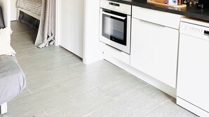 A compact kitchen with white cabinets, a built-in oven, and a dishwasher. A small dining area with a table and chairs is visible. - "BEACH WALK" Air-conditioned, swimming pool, 200m from the beach, parking, wifi (Bandol)