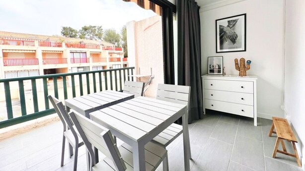 A balcony with a table and chairs, a white dresser, and a cactus decoration. - "BEACH WALK" Air-conditioned, swimming pool, 200m from the beach, parking, wifi (Bandol)