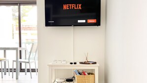 A modern living room with a flat-screen TV mounted on the wall displaying the Netflix logo. - "BEACH WALK" Air-conditioned, swimming pool, 200m from the beach, parking, wifi (Bandol)