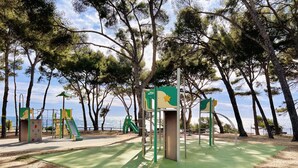 A playground with climbing structures and a slide, surrounded by trees and a view of the sea. - "BEACH WALK" Air-conditioned, swimming pool, 200m from the beach, parking, wifi (Bandol)