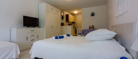 A hotel room with a bed, a TV, a wardrobe, and a small kitchenette.