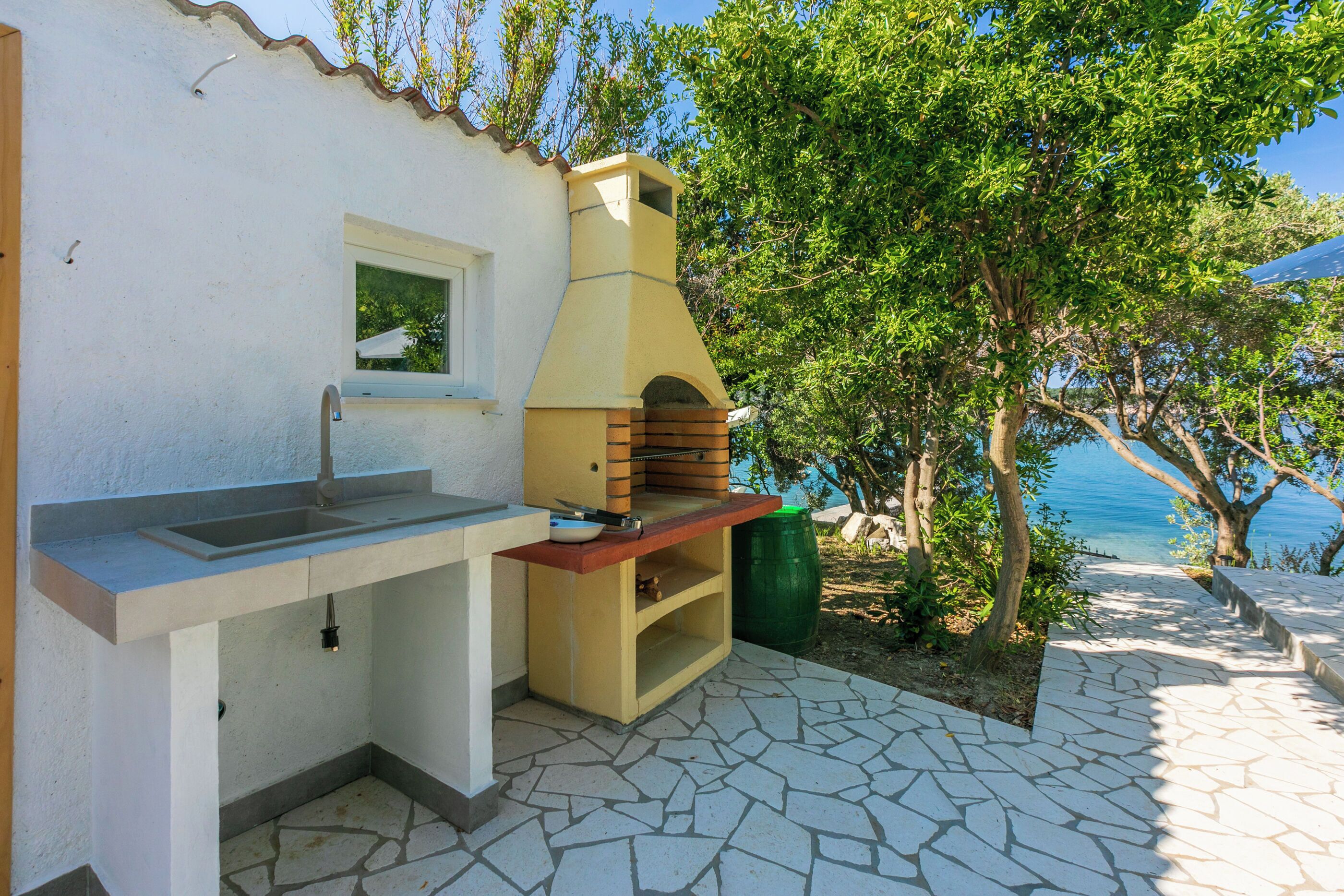 An outdoor kitchen with a stone countertop, a sink, and a pizza oven.
