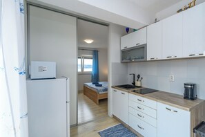 Ett kompakt kök med vita skåp, en träbänkskiva, en diskho och en mikrovågsugn.