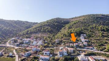 A hillside village with white buildings, a road, and a pool area.