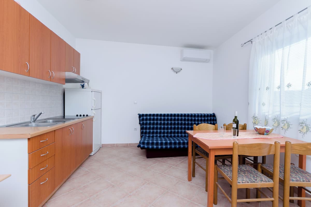 A compact kitchen with wooden cabinets, a white refrigerator, and a dining area with a table and chairs.