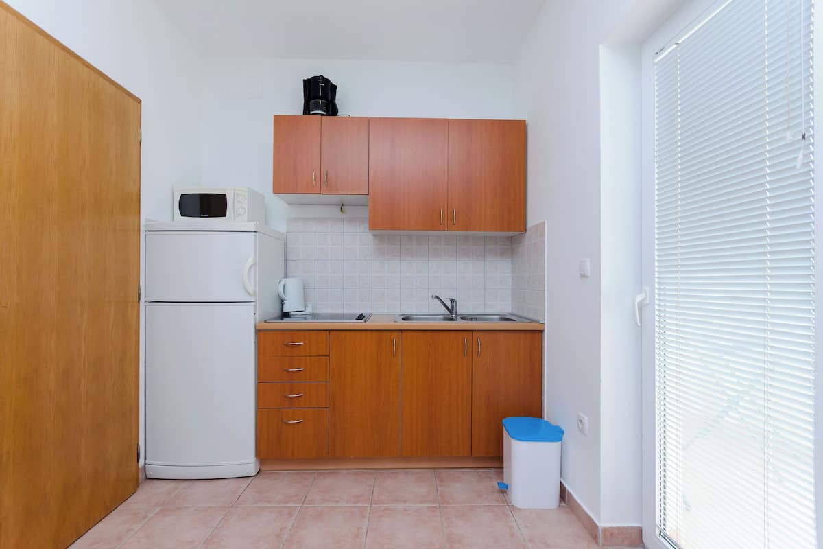 A compact kitchen with wooden cabinets, a white refrigerator, a microwave, and a sink.