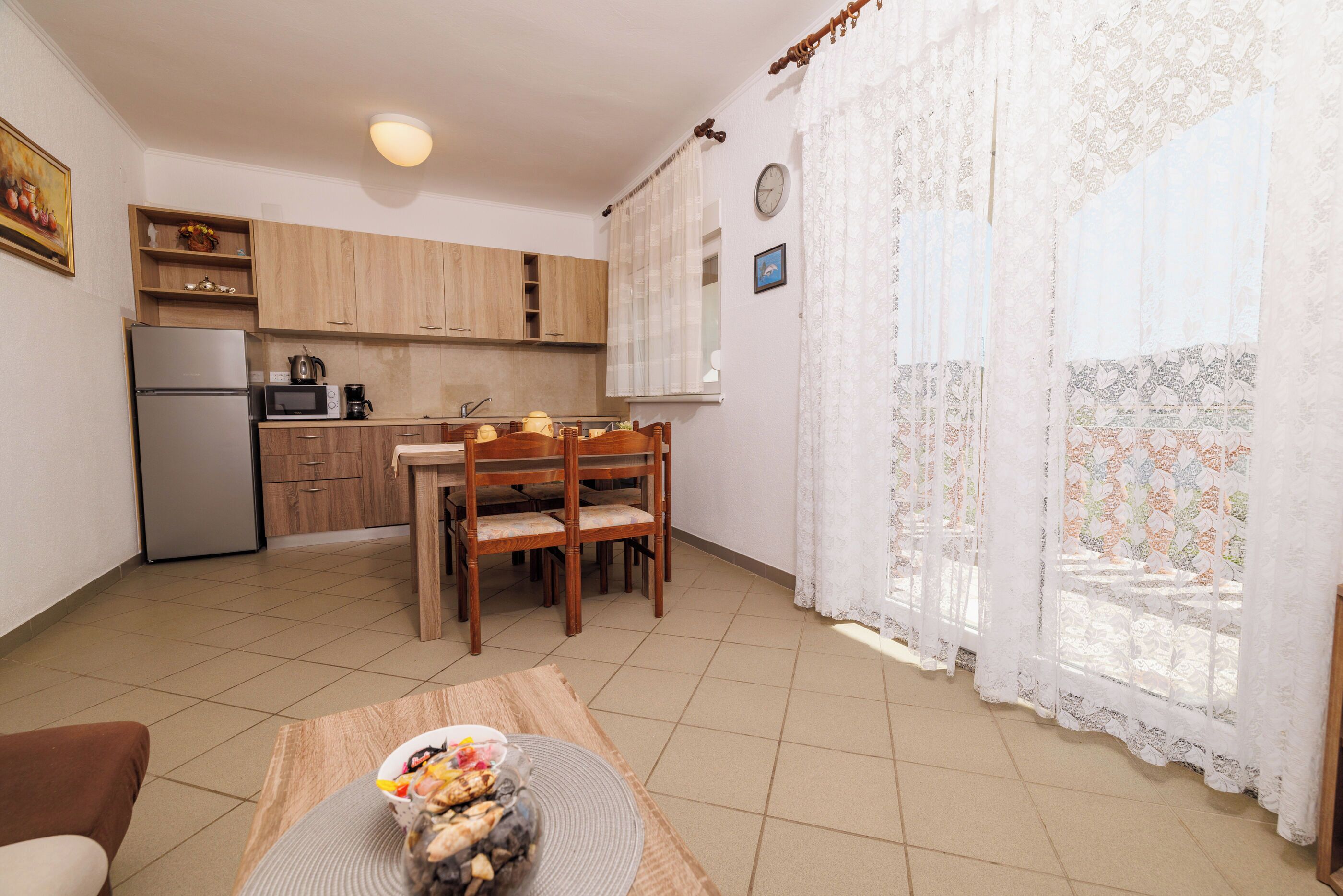 Uma cozinha compacta com armários de madeira, geladeira e um espaço de refeições com mesa e cadeiras.