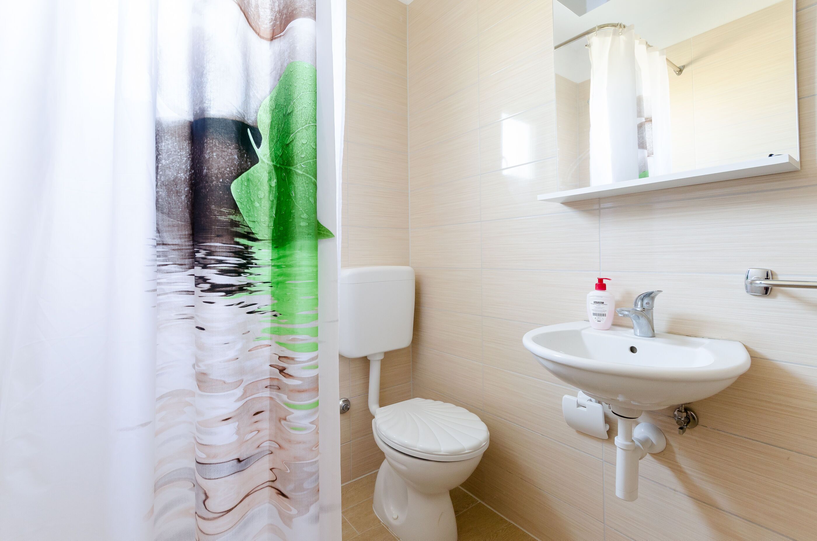 A bathroom with a toilet, sink, and mirror.