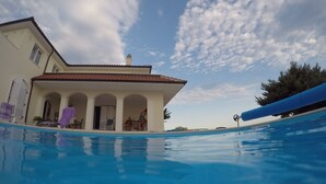 A swimming pool with a house in the background. - Apartments Lanterna (Rogoznica)