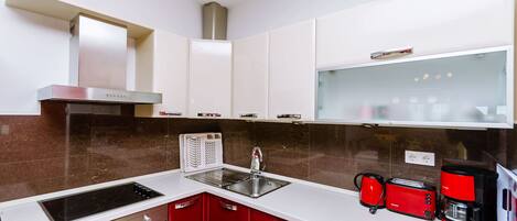 Una cocina moderna con campana de acero inoxidable, horno empotrado, pileta doble y muebles colorados.