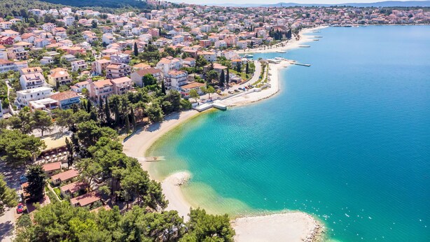 Une ville côtière avec une plage, des maisons et une mer bleue et limpide.