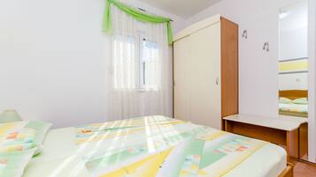 A bedroom with a bed, a desk, a wardrobe, and a mirror.