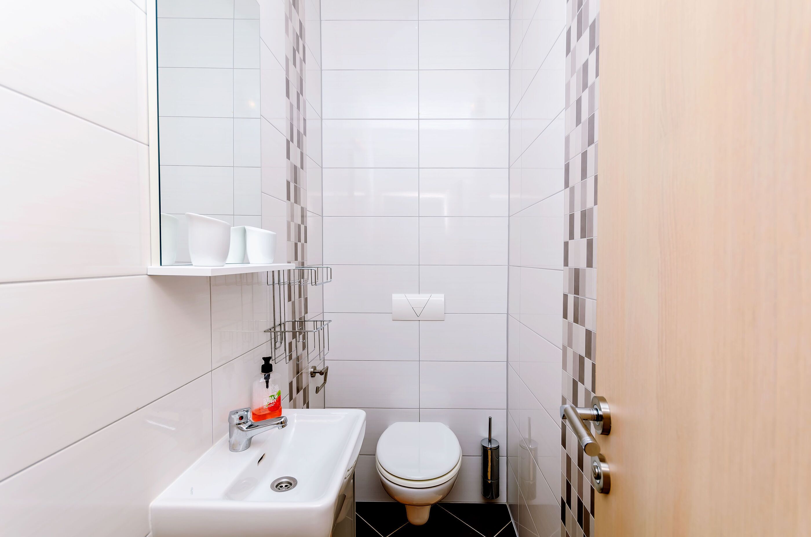 A compact bathroom with a white sink, toilet, and a mirror above the sink.