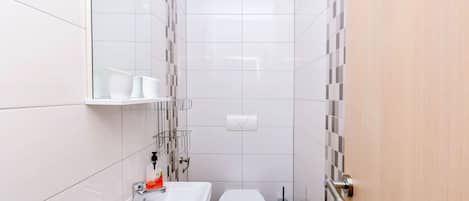 A compact bathroom with a white sink, toilet, and a mirror above the sink.