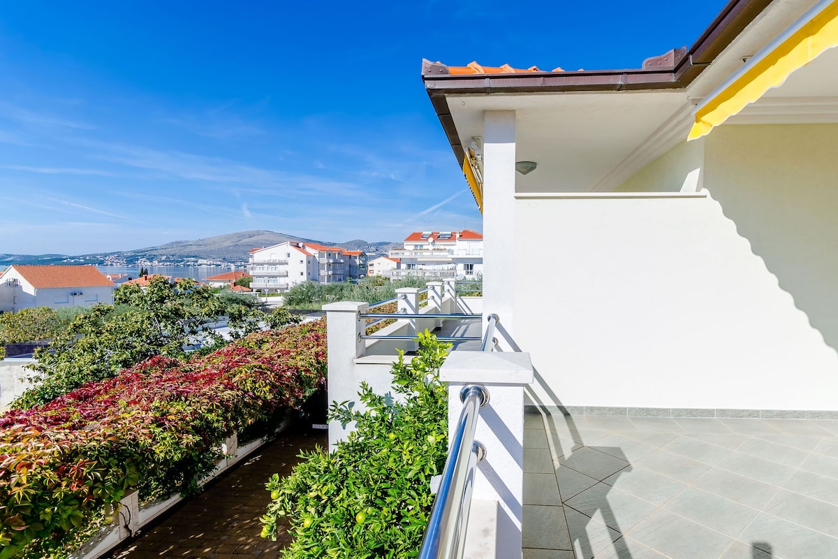 A balcony with a view of a residential area, including houses and a mountain in the distance.