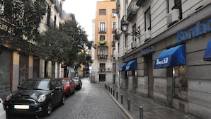 A narrow cobblestone street lined with buildings, including a visible storefront with a blue awning and a sign that reads "Borda".