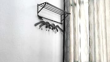 Un dormitorio con una cama, un tendedero de pared y una ventana con cortinas estampadas.