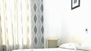 A bedroom with two beds, a radiator, and a framed picture on the wall.