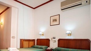 A hotel room with two single beds, wooden headboards, and a wall-mounted air conditioner. - Pensión Carrera (Madrid)