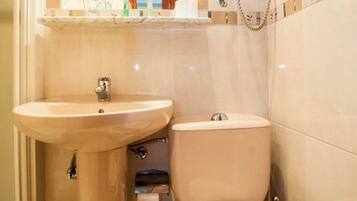 Un baño pequeño con lavamanos pedestal, inodoro y un secamanos de pared.