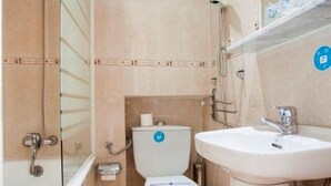 A compact bathroom with a shower, toilet, and sink. - Pensión Carrera (Madrid)
