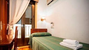 A small room with a bed, a wooden desk, and a chair. - Pensión Carrera (Madrid)