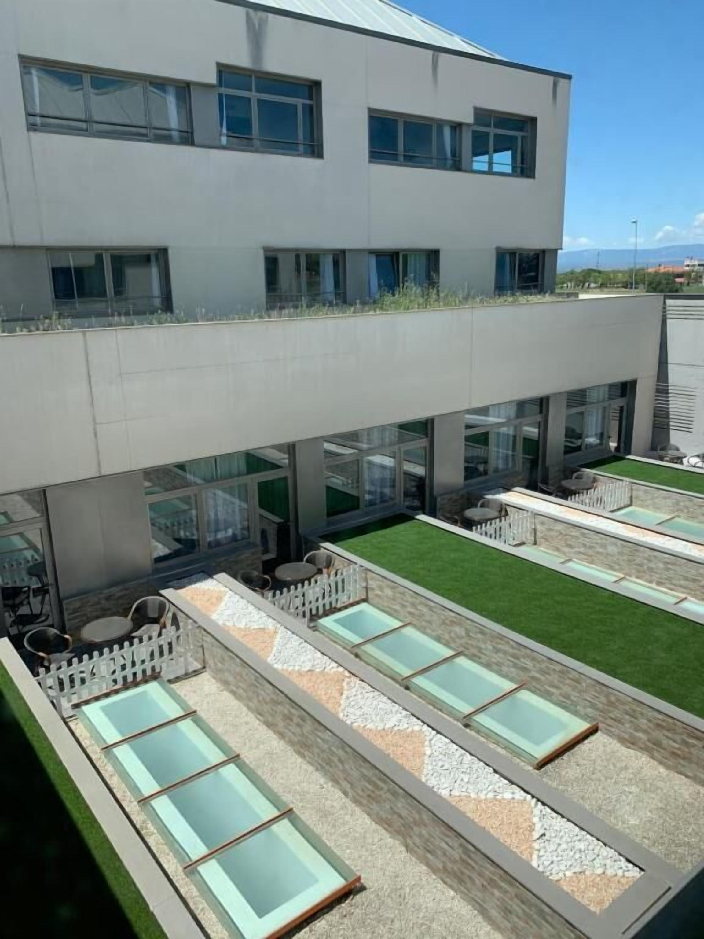 Un edificio moderno con jardín en la azotea, zona de estar exterior y piscina.