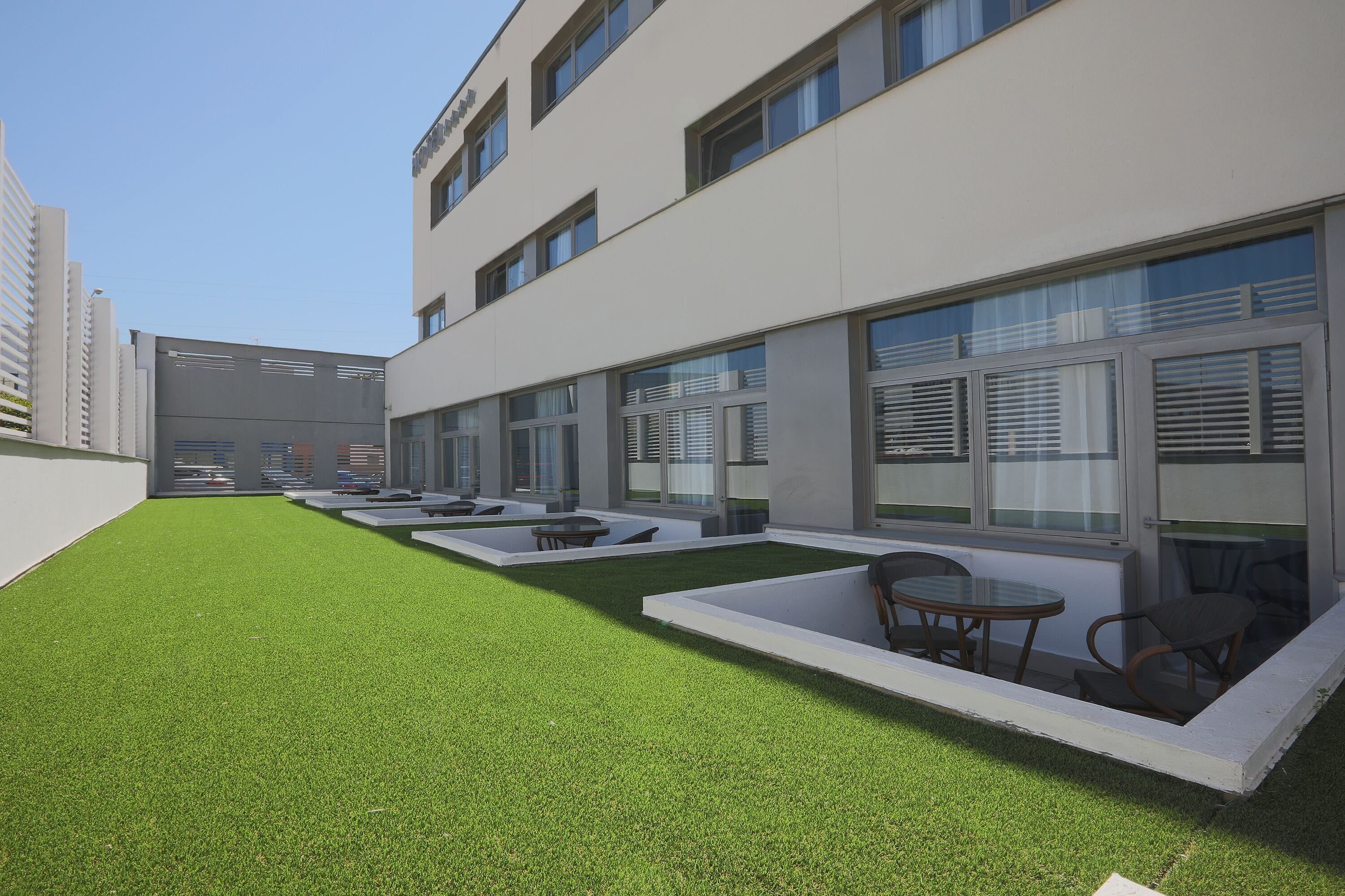 Un edificio moderno con un patio que tiene césped artificial y mobiliario exterior.