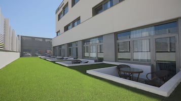 Un edificio moderno con un patio que tiene césped artificial y mobiliario exterior.