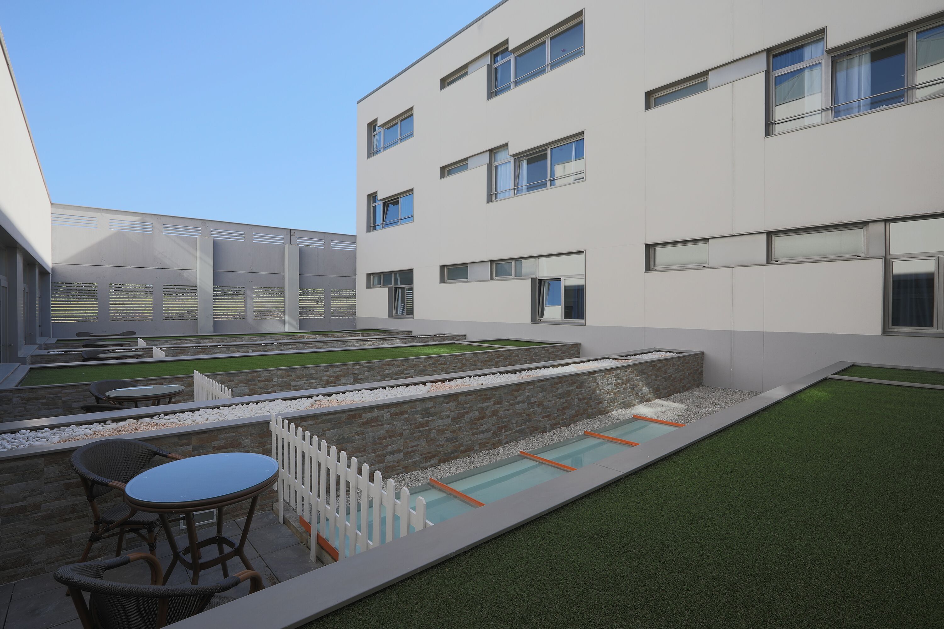 Un edificio moderno con amplias ventanas, piscina y zonas de estar al aire libre.
