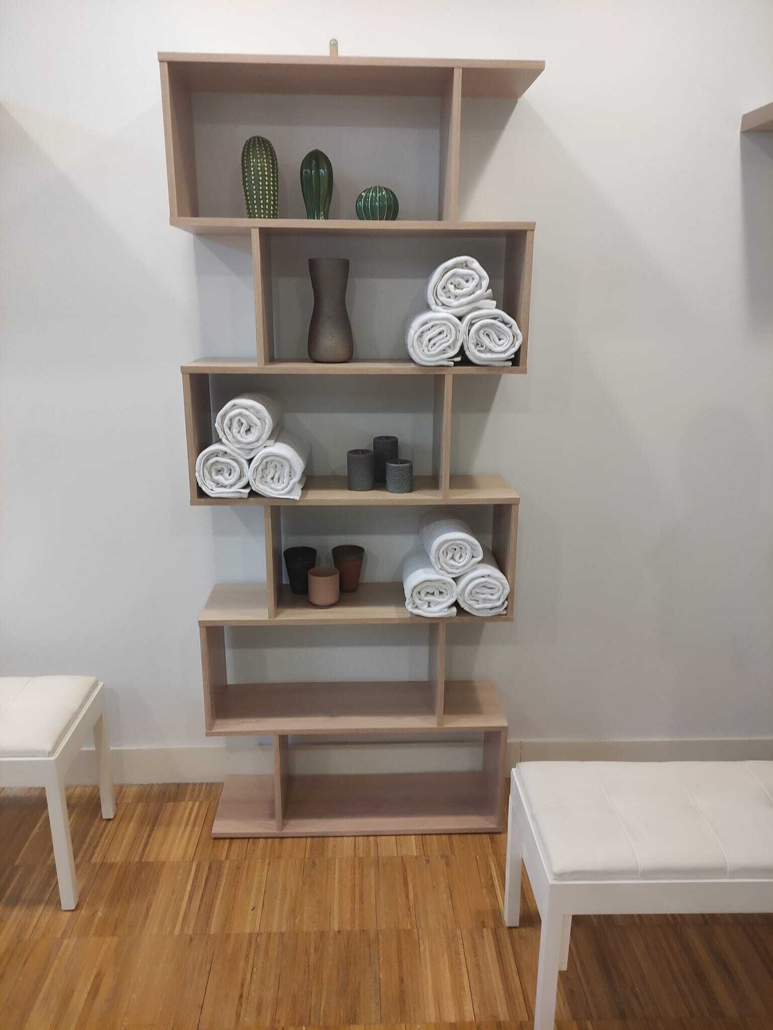 Una estantería de madera con toallas enrolladas y objetos decorativos.