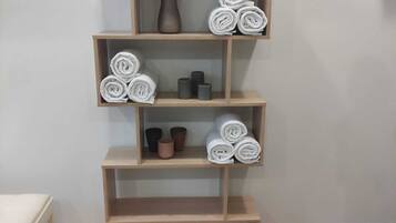 Una estantería de madera con toallas enrolladas y objetos decorativos.