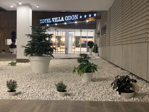 A hotel entrance with a sign reading 'HOTEL VILLA ODON' and a well-maintained gravel area with potted plants. - Hotel Villa Odón (Villaviciosa de Odon)