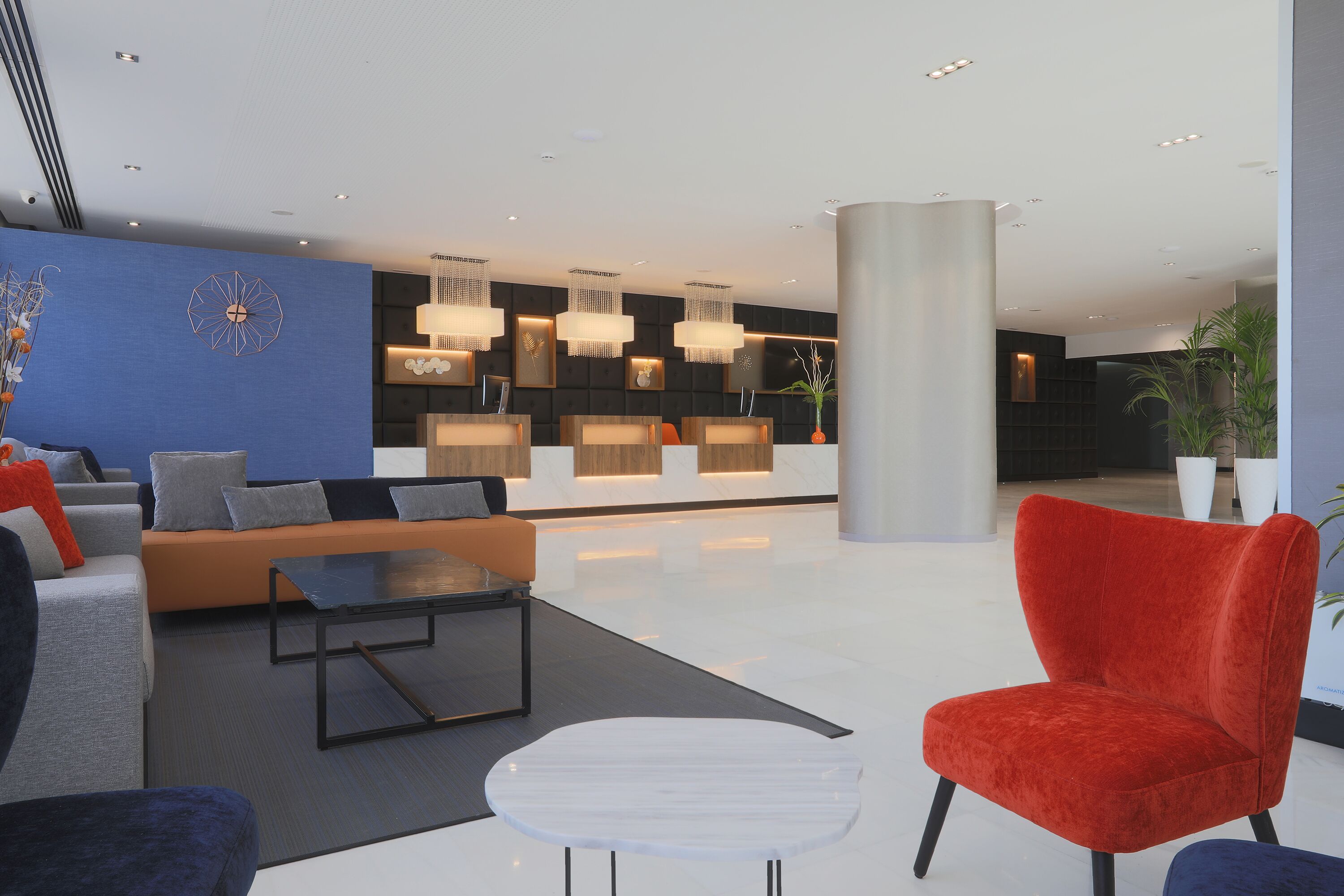 A modern lobby with a reception desk, seating area, and decorative lighting.