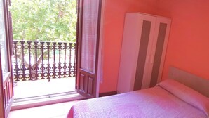 A bedroom with a bed, a wardrobe, and a balcony with a metal railing. - Casa de huéspedes asturiana (Madrid)