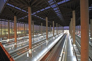 A spacious train station with multiple platforms and a high ceiling supported by large beams. - Casa de huéspedes asturiana (Madrid)